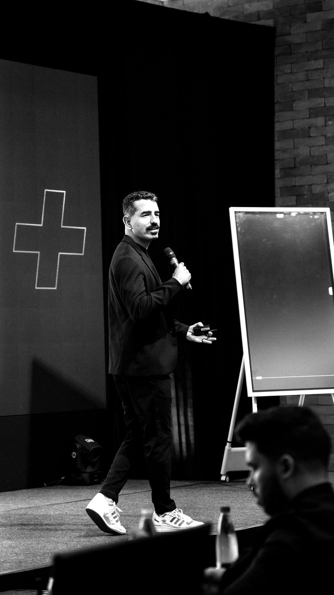 Torres Neto palestrando no palco, com microfone